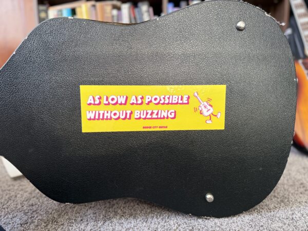 As Low As Possible Without Buzzing sticker on a guitar case